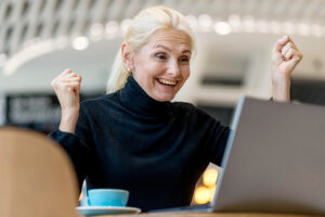 femme qui sourit devant un ordinateur de bureau portable